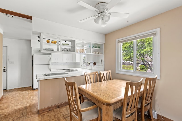 dining room with ceiling fan, baseboards, and bar area
