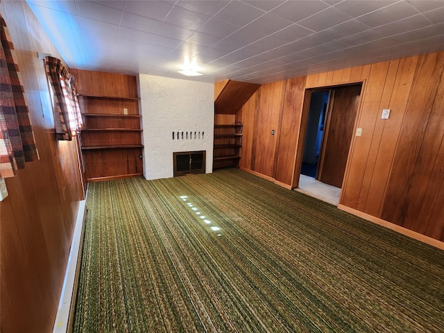 172 Scenery Rd, Libby, MT 59923 - unfurnished living room featuring a large fireplace, wooden walls, carpet floors, and built in shelves