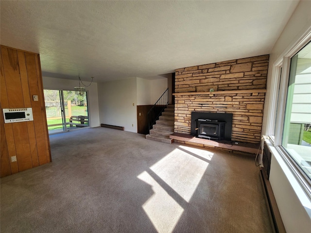172 Scenery Rd, Libby, MT 59923 - unfurnished living room featuring baseboard heating, carpet floors, a chandelier, stairs, and wood walls