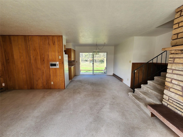 172 Scenery Rd, Libby, MT 59923 - unfurnished living room with a baseboard heating unit, wood walls, carpet, stairway, and a textured ceiling