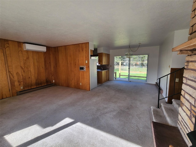 172 Scenery Rd, Libby, MT 59923 - unfurnished living room with baseboard heating, an AC wall unit, carpet floors, wood walls, and stairway