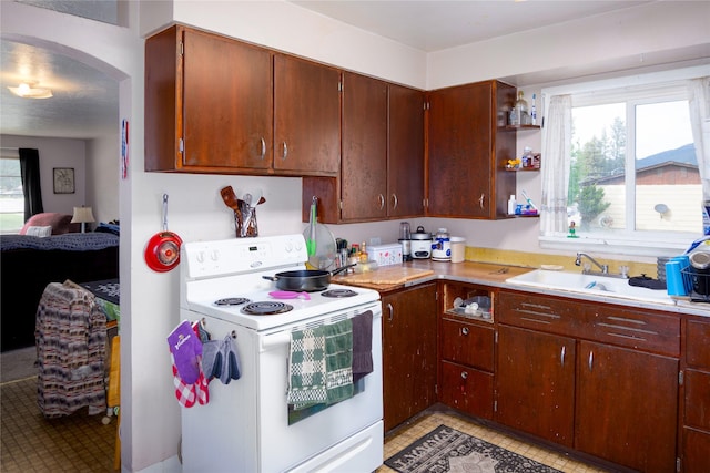 1005 Idaho Ave, Libby, MT 59923 - kitchen featuring white range with electric cooktop, light countertops, a sink, open shelves, and arched walkways
