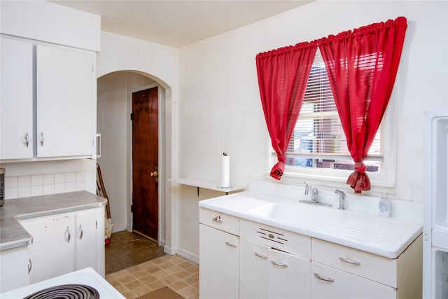 1005 Idaho Ave, Libby, MT 59923 - kitchen with arched walkways, light countertops, white cabinetry, and a sink