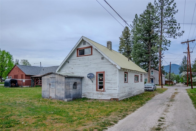 1005 Idaho Ave, Libby, MT 59923 - rear view of property with a chimney, an outbuilding, a shed, and a yard