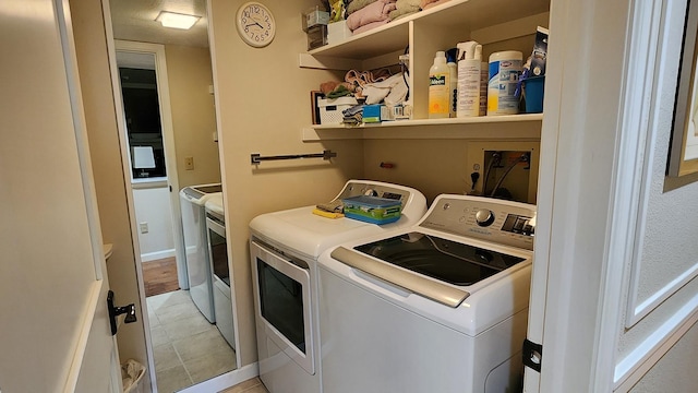 laundry room with washer and dryer and light tile patterned floors