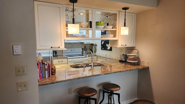 270 Bridge St Unit Qc1-103, Bigfork, MT 59911 - kitchen with white electric range, light stone counters, white cabinets, and a peninsula