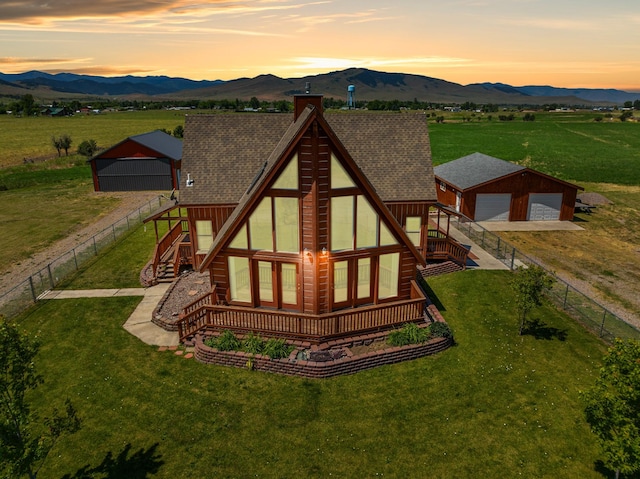 61253 Watson Rd, Saint Ignatius, MT 59865 - back of property at dusk with an outbuilding, a mountain view, a chimney, a detached garage, and stairs