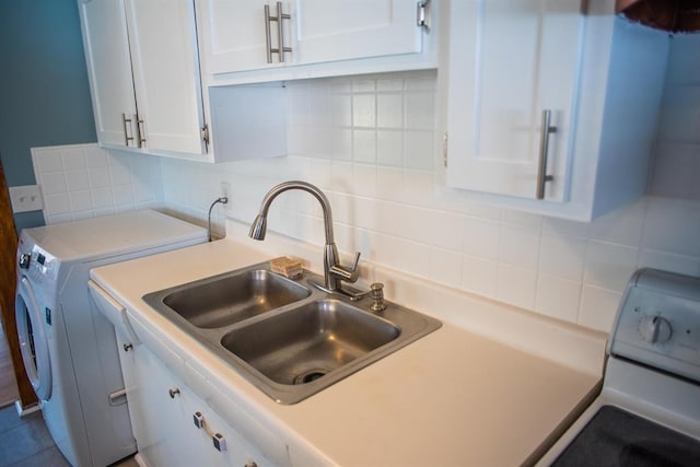 kitchen featuring stove, separate washer and dryer, white cabinets, a sink, and backsplash
