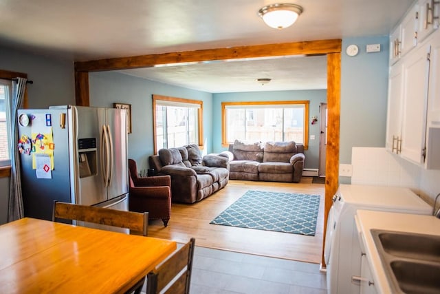 living area featuring independent washer and dryer, a baseboard radiator, beamed ceiling, and tile patterned floors