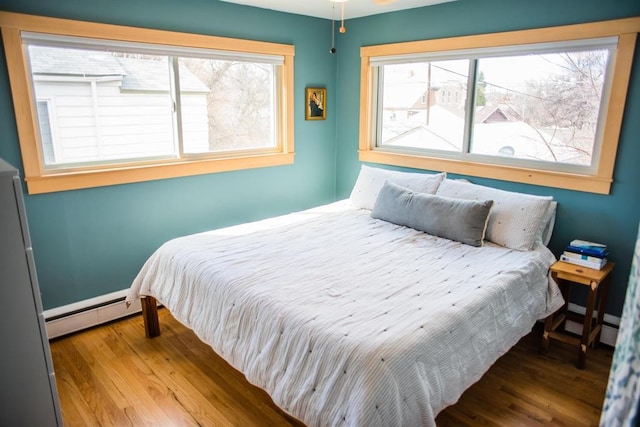 bedroom featuring baseboard heating and wood finished floors