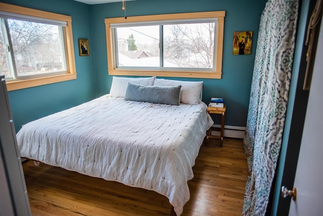 bedroom with wood finished floors and a baseboard radiator