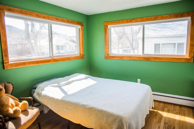 bedroom featuring baseboard heating and wood finished floors