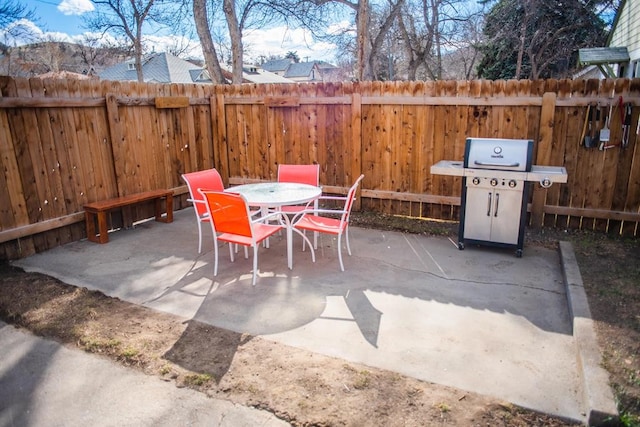 view of patio featuring area for grilling, fence, and outdoor dining area