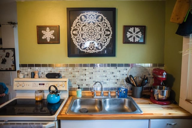 kitchen with white range with electric stovetop, a sink, tasteful backsplash, and light countertops