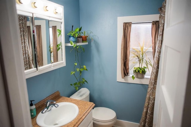 bathroom with toilet, healthy amount of natural light, vanity, and baseboards