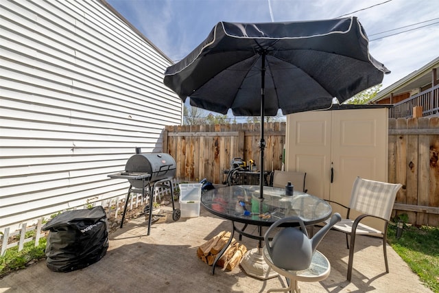 view of patio featuring a storage unit, fence, an outbuilding, area for grilling, and outdoor dining area