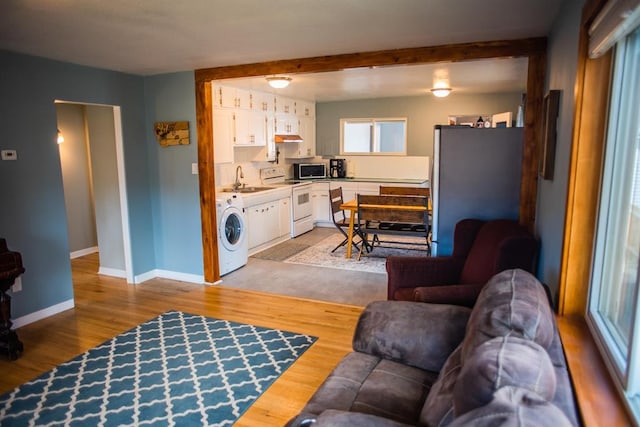 living room with washer / clothes dryer, baseboards, and light wood finished floors
