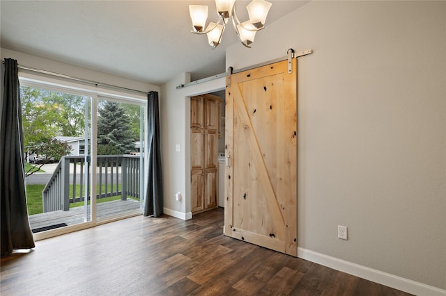 empty room featuring dark wood finished floors, baseboards, a barn door, a chandelier, and vaulted ceiling