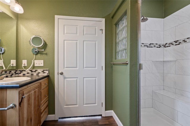 bathroom featuring a stall shower, decorative backsplash, vanity, and wood finished floors