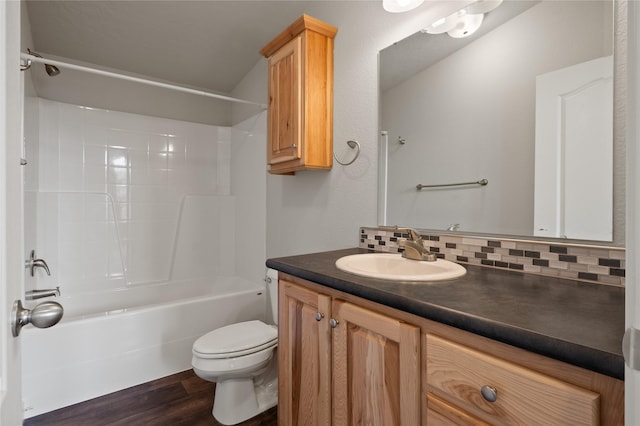 bathroom featuring wood finished floors, toilet, decorative backsplash, vanity, and shower / bath combination