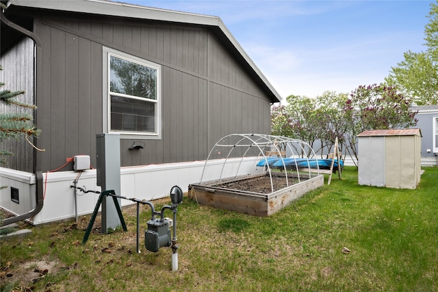 view of side of home with a garden, a yard, an outdoor structure, and a storage unit