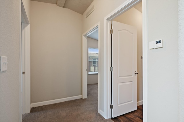 hallway with dark colored carpet and baseboards