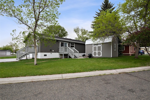 manufactured / mobile home with a front lawn, a shed, an outbuilding, and stairs