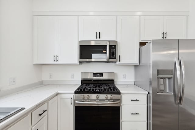kitchen featuring stainless steel appliances, white cabinetry, and light stone counters