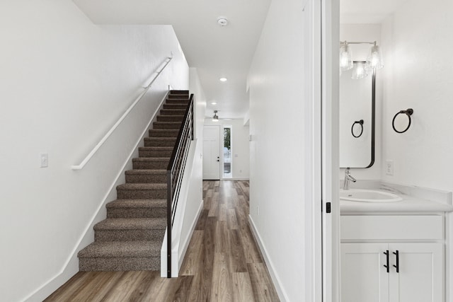 stairway featuring wood finished floors, recessed lighting, and baseboards