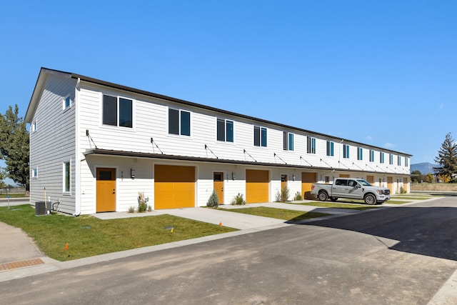 townhome / multi-family property featuring central air condition unit, an attached garage, and driveway