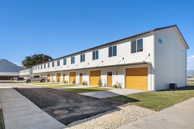 townhome / multi-family property featuring an attached garage, asphalt driveway, a mountain view, and central AC