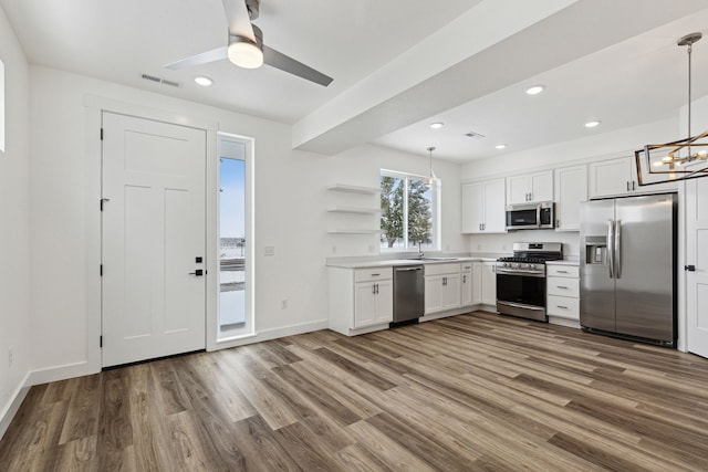 kitchen featuring appliances with stainless steel finishes, wood finished floors, open shelves, white cabinetry, and light countertops