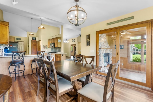 1815 Homestead Dr, Missoula, MT 59808 - dining area with wood finished floors, a chandelier, vaulted ceiling, a fireplace, and a ceiling fan