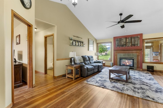 1815 Homestead Dr, Missoula, MT 59808 - living room featuring a ceiling fan, wood finished floors, a tiled fireplace, high vaulted ceiling, and baseboards
