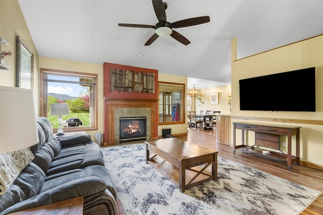 1815 Homestead Dr, Missoula, MT 59808 - living room with vaulted ceiling, a tiled fireplace, wood finished floors, a ceiling fan, and a chandelier