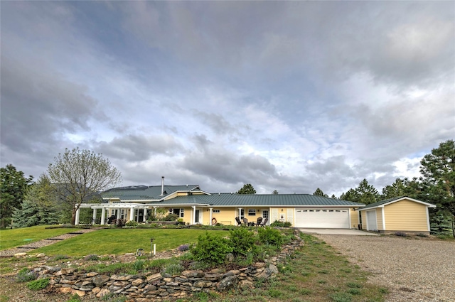 single story home with driveway, an attached garage, a front yard, and metal roof