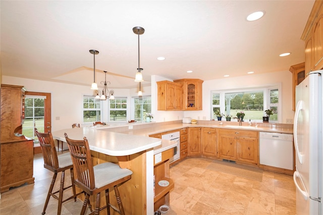 kitchen featuring white appliances, light countertops, a kitchen bar, healthy amount of natural light, and recessed lighting