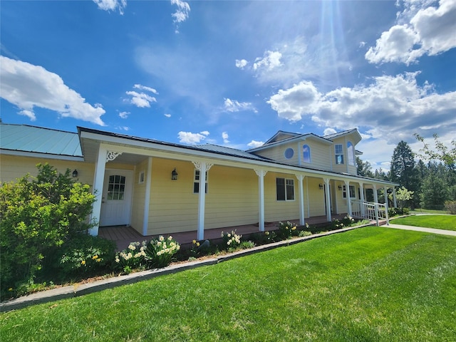 farmhouse-style home featuring covered porch, a front yard, and metal roof