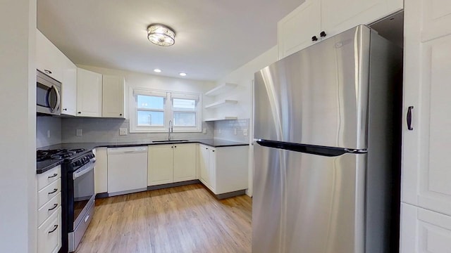 1240 Cannon St, Helena, MT 59601 - kitchen featuring appliances with stainless steel finishes, a sink, dark countertops, light wood-type flooring, and tasteful backsplash