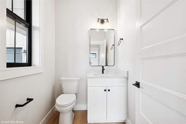 bathroom featuring baseboards, toilet, vanity, and wood finished floors
