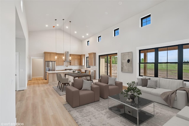 living area with high vaulted ceiling, light wood-style flooring, and recessed lighting