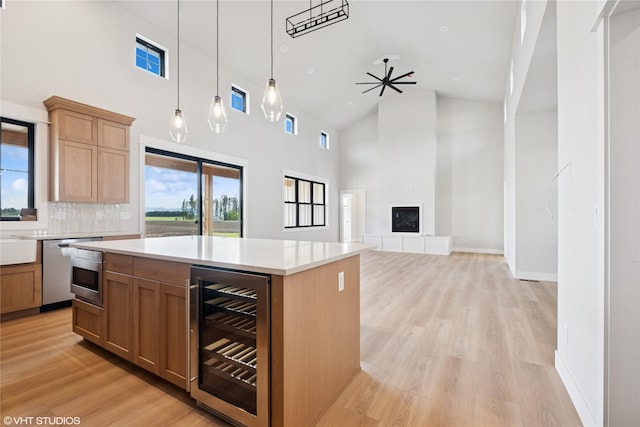 kitchen featuring wine cooler, high vaulted ceiling, light wood finished floors, light countertops, and a center island