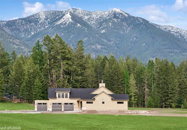 168 Wood Ridge Dr, Columbia Falls, MT 59912 - view of front facade featuring a front lawn, a wooded view, a mountain view, and a garage