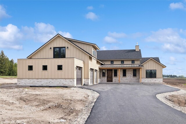 168 Wood Ridge Dr, Columbia Falls, MT 59912 - modern inspired farmhouse featuring a standing seam roof, board and batten siding, stone siding, asphalt driveway, and a metal roof
