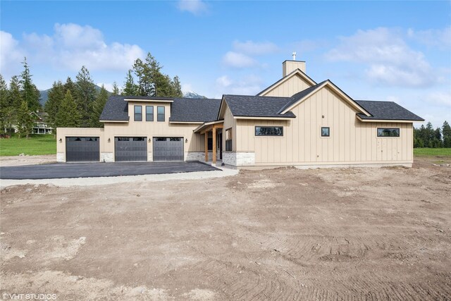 168 Wood Ridge Dr, Columbia Falls, MT 59912 - modern farmhouse featuring board and batten siding, a chimney, roof with shingles, and driveway