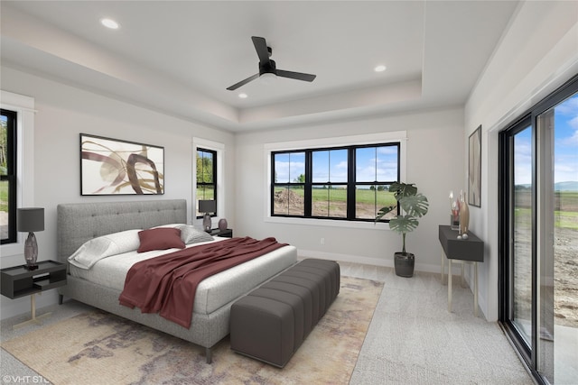 bedroom with multiple windows, a tray ceiling, recessed lighting, light colored carpet, and baseboards