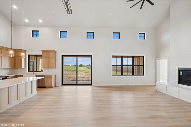 168 Wood Ridge Dr, Columbia Falls, MT 59912 - unfurnished living room featuring a towering ceiling, light wood-type flooring, healthy amount of natural light, recessed lighting, and a ceiling fan