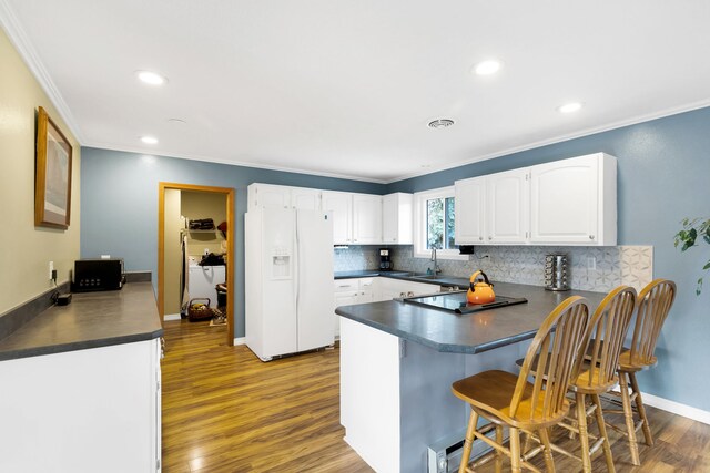 4003 Thomas Pl, Missoula, MT 59803 - kitchen featuring white fridge with ice dispenser, a peninsula, dark countertops, ornamental molding, and wood finished floors