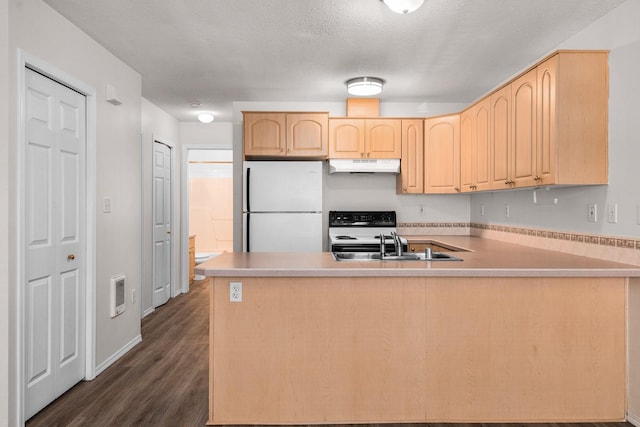 kitchen with freestanding refrigerator, under cabinet range hood, light brown cabinetry, a peninsula, and a sink