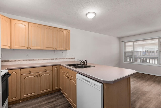 kitchen featuring white dishwasher, a sink, a peninsula, stove, and light brown cabinetry